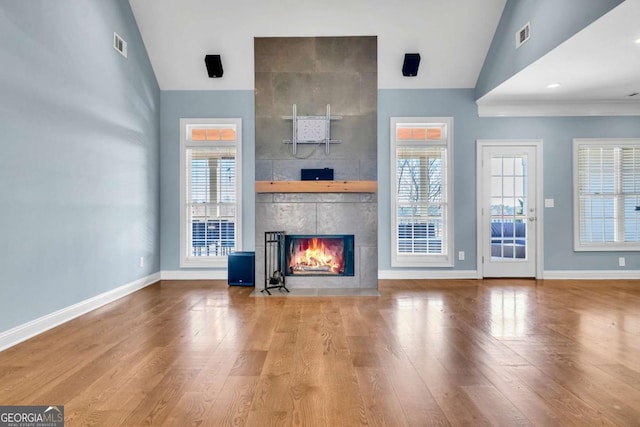 unfurnished living room featuring a fireplace, a wealth of natural light, and wood finished floors