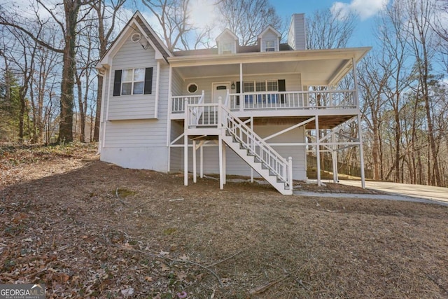 view of front facade featuring covered porch, a chimney, and stairway