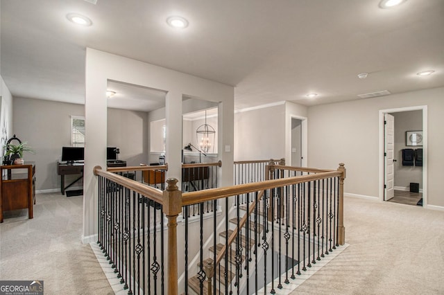 hall featuring carpet floors, baseboards, and an upstairs landing