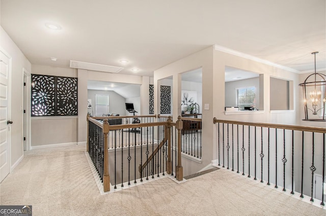 hall featuring attic access, baseboards, carpet, an upstairs landing, and a notable chandelier