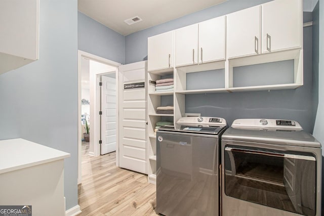 laundry area featuring light wood-type flooring, cabinet space, visible vents, and independent washer and dryer
