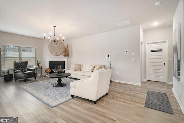 living area featuring baseboards, a glass covered fireplace, light wood-style floors, a chandelier, and recessed lighting