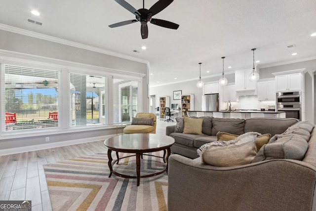 living room with crown molding, recessed lighting, visible vents, light wood-style flooring, and baseboards