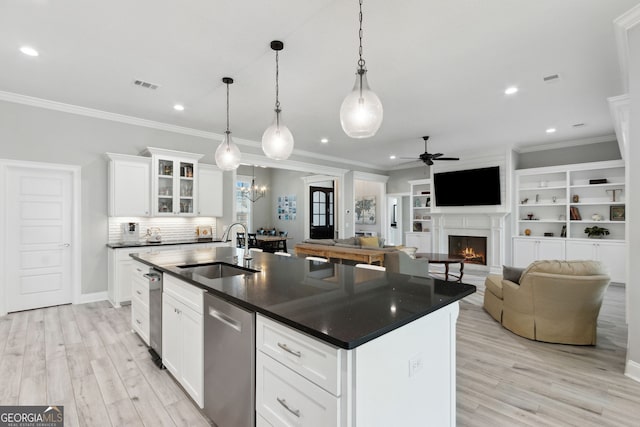 kitchen featuring dishwasher, dark countertops, a sink, and visible vents