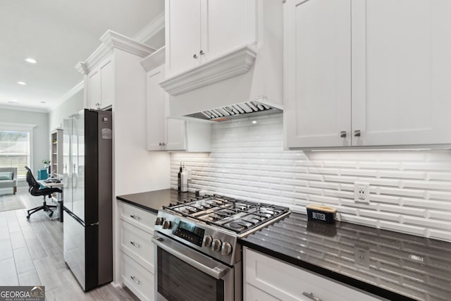 kitchen featuring crown molding, decorative backsplash, freestanding refrigerator, white cabinets, and stainless steel gas range