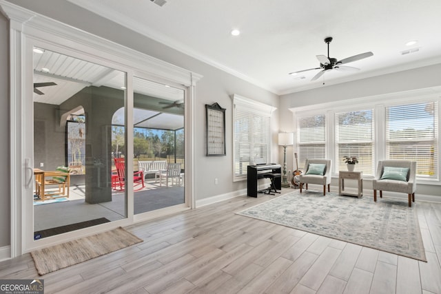 sitting room featuring crown molding, visible vents, a sunroom, ceiling fan, and wood finished floors