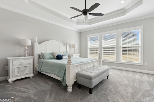 bedroom featuring baseboards, a ceiling fan, a tray ceiling, crown molding, and dark carpet