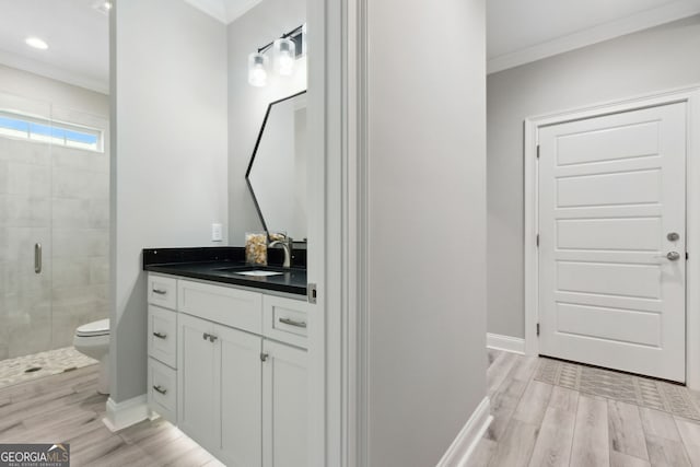 full bath with crown molding, a shower stall, vanity, wood finished floors, and baseboards