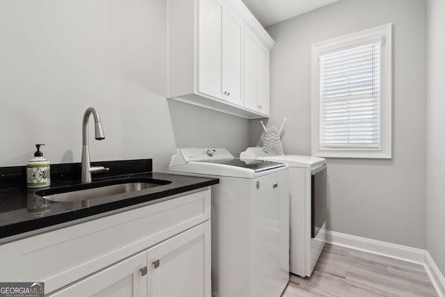 washroom with cabinet space, baseboards, independent washer and dryer, light wood-type flooring, and a sink