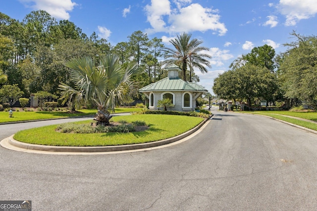 view of front of home featuring a front yard, a standing seam roof, curved driveway, and metal roof