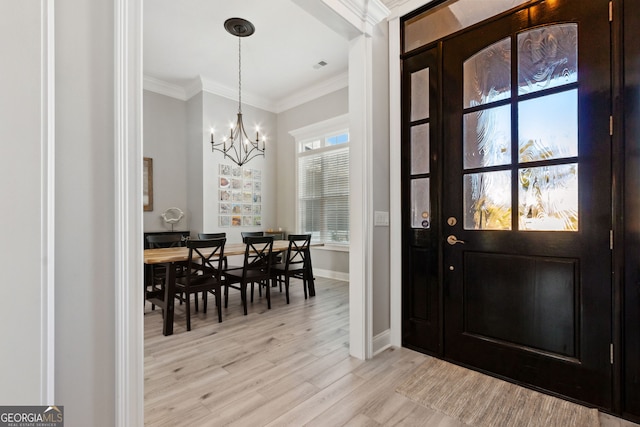 foyer with a chandelier, ornamental molding, baseboards, and light wood-style floors