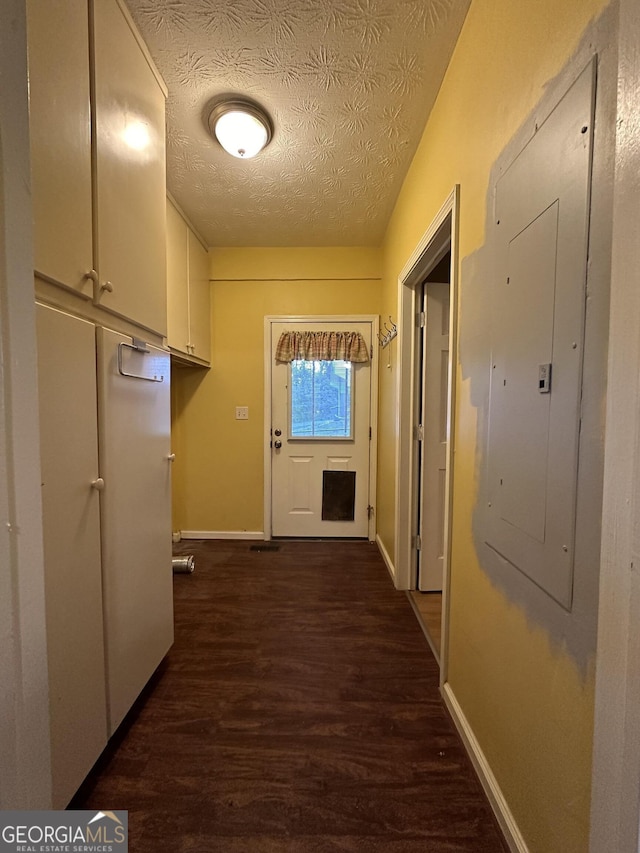 corridor with electric panel, baseboards, dark wood finished floors, and a textured ceiling