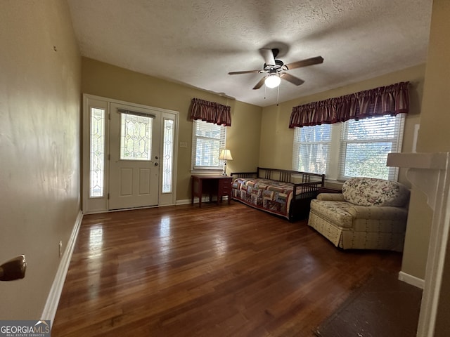 living area featuring a textured ceiling, ceiling fan, wood finished floors, and a wealth of natural light