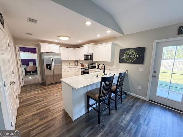 kitchen with stainless steel appliances, a peninsula, a sink, visible vents, and dark wood-style floors