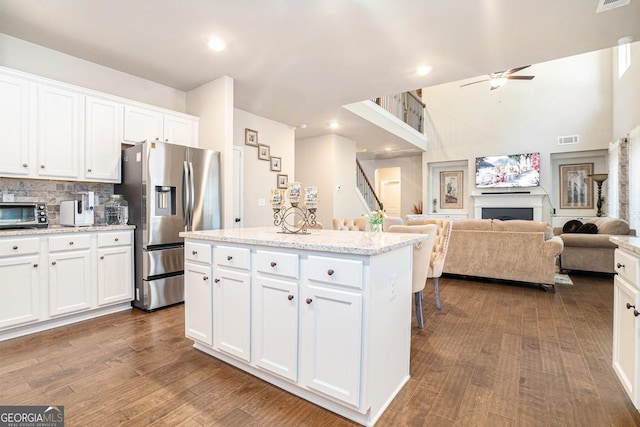 kitchen featuring a fireplace, visible vents, dark wood-type flooring, and stainless steel fridge with ice dispenser