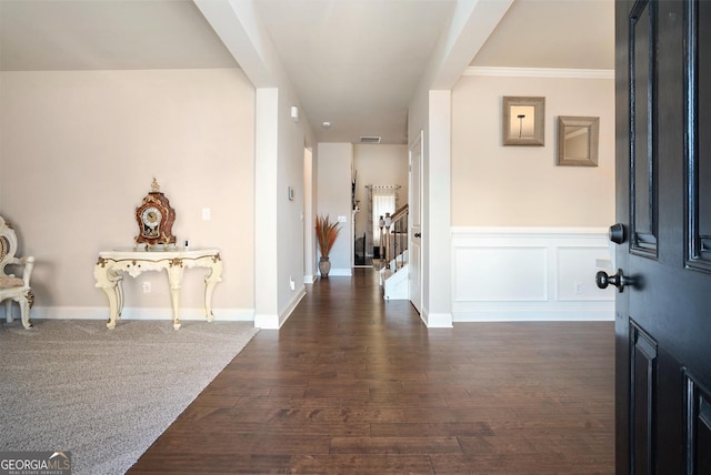 entrance foyer with stairs, dark wood-type flooring, a wainscoted wall, and a decorative wall