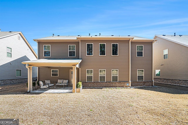 rear view of property featuring brick siding, a yard, an outdoor hangout area, and a patio