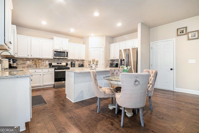 kitchen with a center island, stainless steel appliances, backsplash, dark wood-type flooring, and a sink