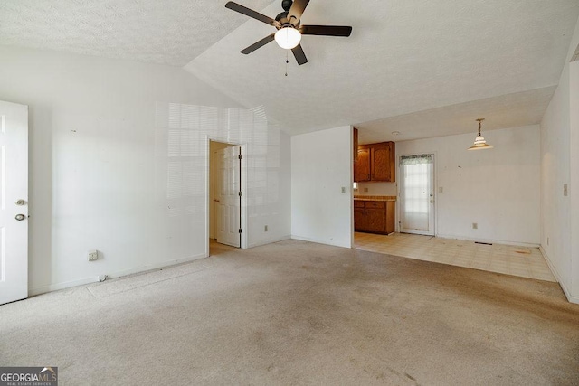 unfurnished living room featuring vaulted ceiling, a textured ceiling, a ceiling fan, and light colored carpet