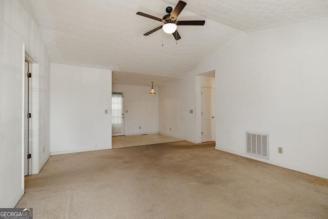 unfurnished living room with lofted ceiling, a textured ceiling, carpet floors, visible vents, and a ceiling fan