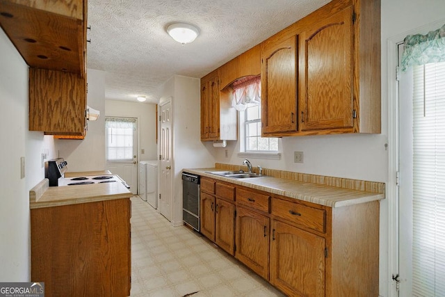 kitchen featuring electric range, a sink, independent washer and dryer, dishwasher, and light floors