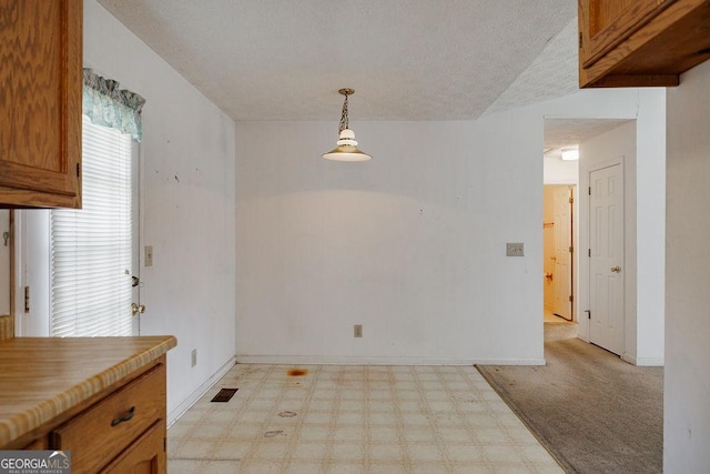 dining space with baseboards, a textured ceiling, and light floors