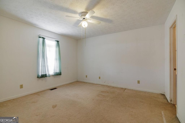 empty room featuring light carpet, ceiling fan, a textured ceiling, and baseboards