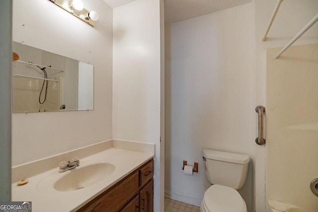 bathroom featuring a shower, baseboards, vanity, and toilet