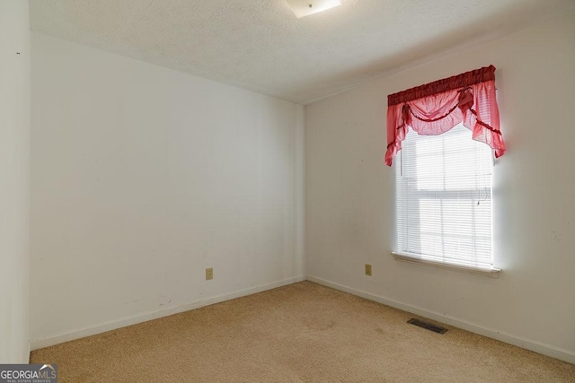 empty room with baseboards, carpet, visible vents, and a textured ceiling