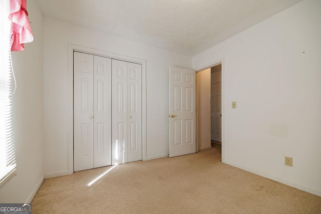 unfurnished bedroom featuring carpet floors, a closet, and baseboards