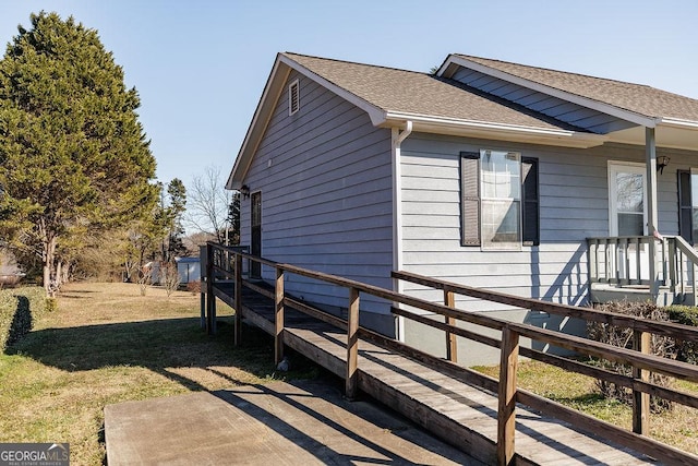 view of side of home featuring a yard and a shingled roof