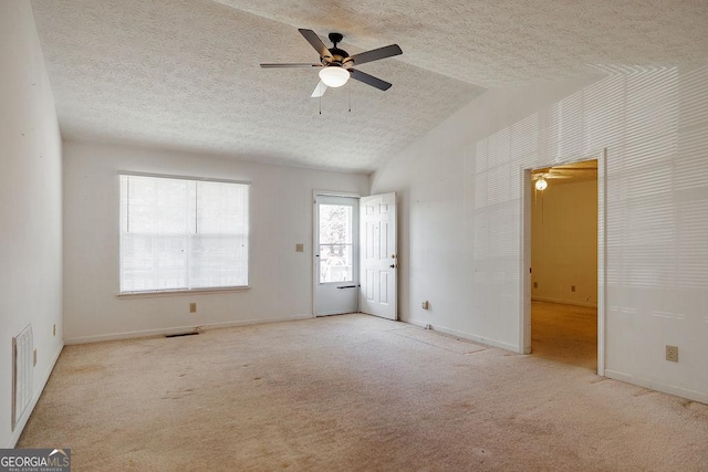 empty room with lofted ceiling, carpet, visible vents, and a textured ceiling