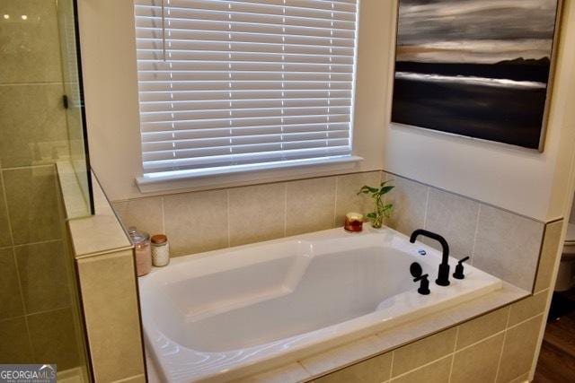 bathroom with a bath and tiled shower