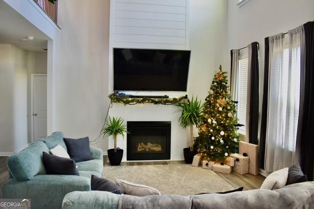 living room featuring a wealth of natural light, a fireplace, a high ceiling, and wood finished floors