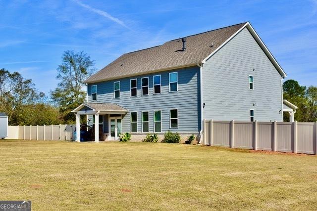 rear view of house with a yard and fence