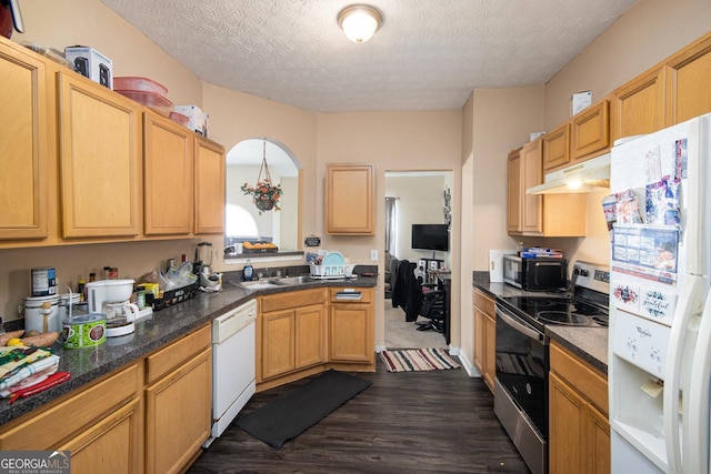 kitchen featuring dark wood-style flooring, dark countertops, a textured ceiling, white appliances, and under cabinet range hood