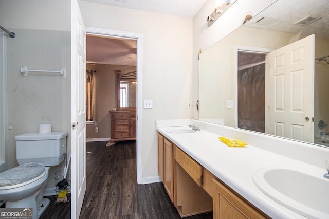 full bathroom with toilet, double vanity, a sink, and visible vents