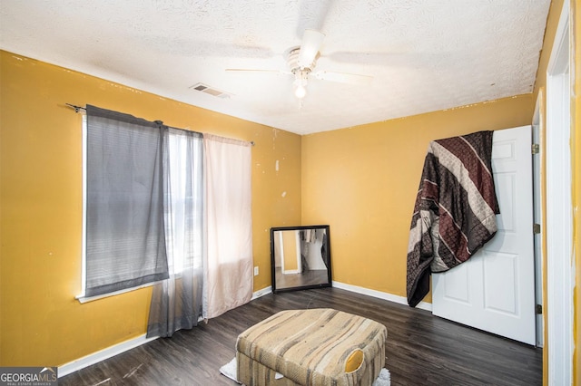 living area with visible vents, baseboards, and wood finished floors