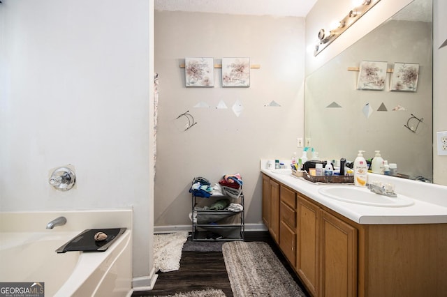 full bath with a bathing tub, baseboards, wood finished floors, and vanity