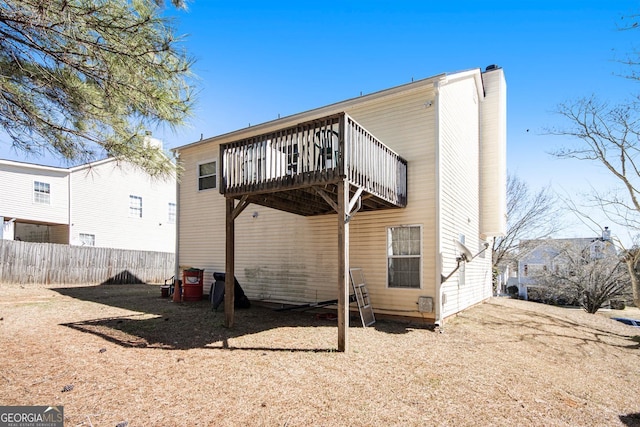 back of house featuring a deck, a chimney, and fence