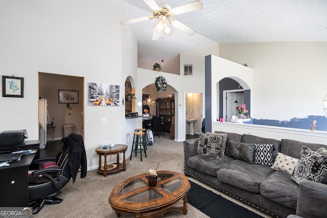 living area featuring arched walkways, a textured ceiling, visible vents, a ceiling fan, and carpet