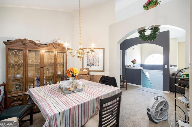 carpeted dining space featuring arched walkways, a towering ceiling, baseboards, and an inviting chandelier