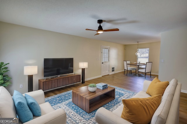 living area with ceiling fan, baseboards, and wood finished floors