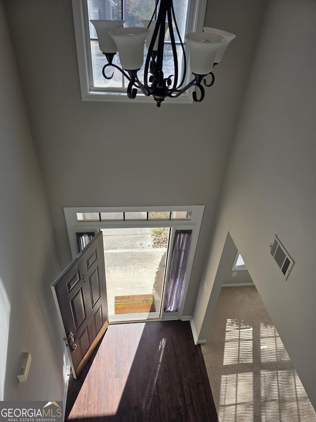 foyer featuring a towering ceiling, plenty of natural light, visible vents, and a notable chandelier