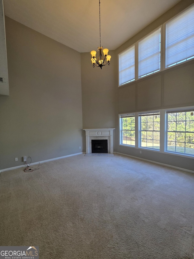 unfurnished living room with a chandelier, carpet floors, a fireplace with flush hearth, and baseboards