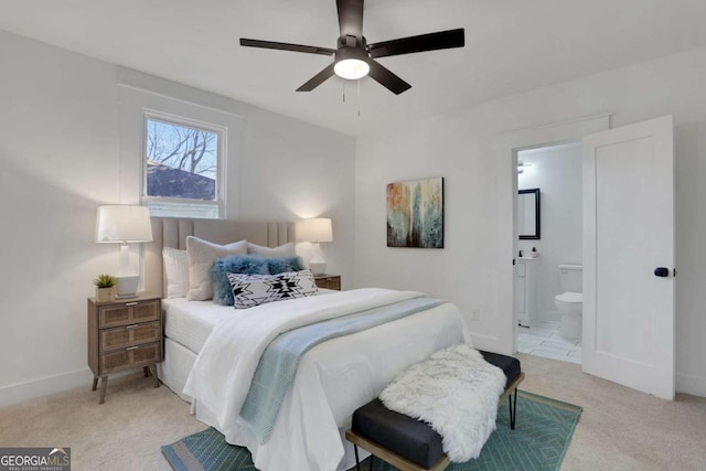 bedroom with light carpet, ceiling fan, baseboards, and ensuite bathroom