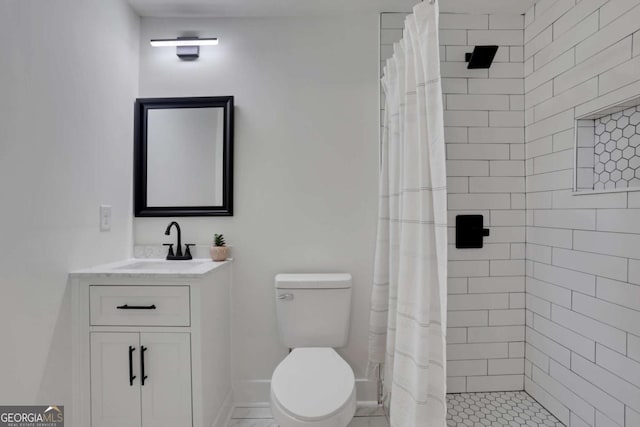 bathroom with tiled shower, vanity, toilet, and baseboards