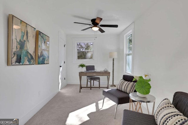 carpeted office space featuring ceiling fan and baseboards