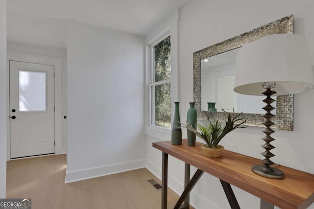 doorway to outside featuring light wood-type flooring, visible vents, and baseboards