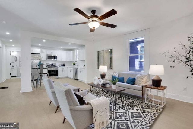 living area with light wood-style flooring, baseboards, ceiling fan, and recessed lighting